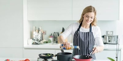 Happy woman cooking at home wearing an apron - healthy eating concepts